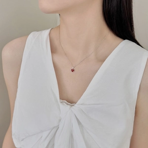 Detail of red heart agate pendant on S925 silver chain worn by a model in white