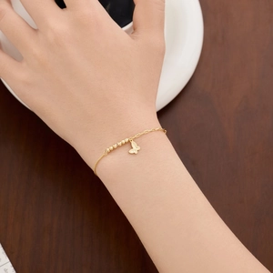Detail of S925 silver gold butterfly pendant bracelet worn by a model in a cozy setting