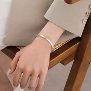 Minimalist S925 sterling silver bangle with star-hammered texture worn by model