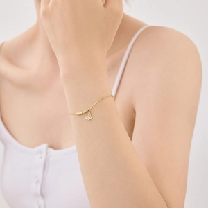 Close-up of golden butterfly pendant bracelet with round beads on a model wrist