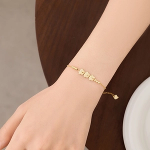 Detail of S925 silver bracelet featuring golden flower charms and a heart pendant on wrist