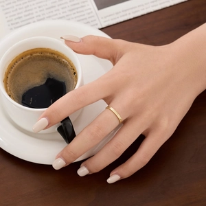 Close-up of a textured gold stacking ring worn elegantly while holding a coffee cup