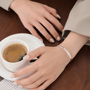 Detail of minimalist S925 sterling silver bangle with elegant textured ripple pattern