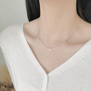 Detail of S925 silver smiley face necklace with red stone on elegant woman's neck