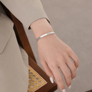 Minimalist S925 sterling silver open bangle with delicate wave pattern worn by woman
