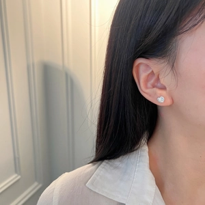 Detail view of heart-shaped S925 sterling silver earrings with 5mm zircon on ear lobe