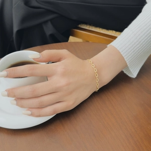 Detailed view of dainty gold sterling silver chain bracelet worn during daily coffee time