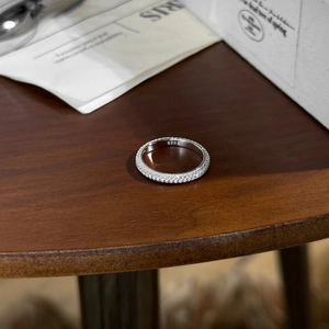 Dettaglio macro dell'anello in argento S925 con pavé di moissanite su piano in legno