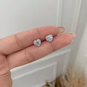 Close-up of S925 sterling silver heart halo stud earrings held in hand for scale