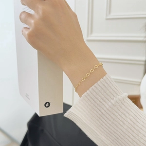 Detail of elegant gold-toned textured chain bracelet worn on wrist with minimalist style