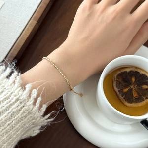 Close-up of a delicate gold S925 silver chain bracelet with small white pearls