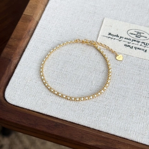 Detail of S925 sterling silver tag and woven gold chain on a minimalist bracelet