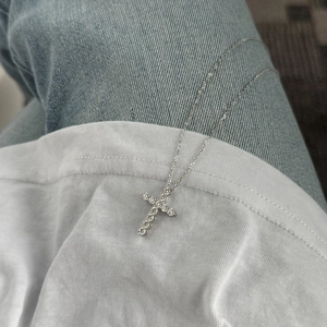 Gros plan du collier croix en argent 925 avec pierres moissanite pavées sur tissu denim