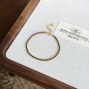 Detailed close-up of woven gold metal chain with black cord and heart pendant