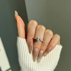 Close-up of 2 carat heart-shaped moissanite silver ring on woman's hand with knit sweater