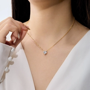 Gros plan d'un collier en argent S925 doré avec pendentif cœur sur la clavicule