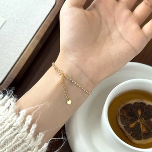 Delicate gold link bracelet with sparkling gems and heart charm on a female wrist