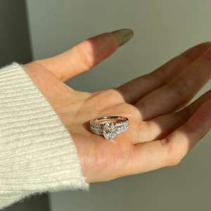 Close-up of 2-carat oval moissanite ring in S925 silver held in hand with sunlight