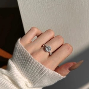 Gros plan d'une bague halo en argent S925 avec moissanite de 1,2 carat sur un pull blanc