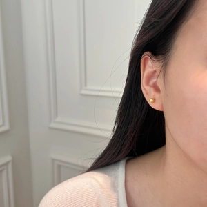 Puce d'oreille boule en argent S925 doré portée par un mannequin pour un look raffiné