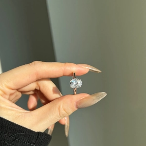 Close-up of a 3-carat oval moissanite ring in rose gold four-prong setting under sunlight