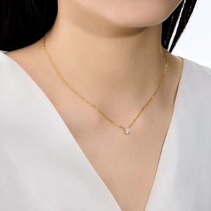 Vue détaillée d'un collier pendentif cœur doré avec zircon porté par un mannequin