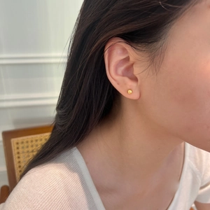 Gros plan de boucles d'oreilles boules minimalistes en argent S925 doré portées à l'oreille