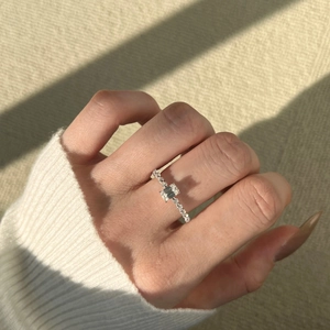 Close-up of emerald cut moissanite silver ring worn on hand with knitted sleeve