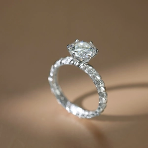 Detail of a 2-carat moissanite ring with six-prong setting and twisted pavé band