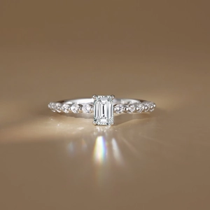Detailed view of emerald cut gemstone ring featuring side accent diamonds and rainbow fire