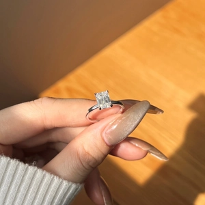 Close-up of emerald cut moissanite engagement ring in 925 sterling silver setting