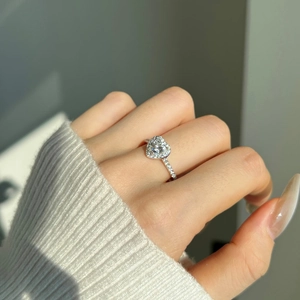 Gros plan d'une bague coeur en argent et moissanite portée avec pierres latérales