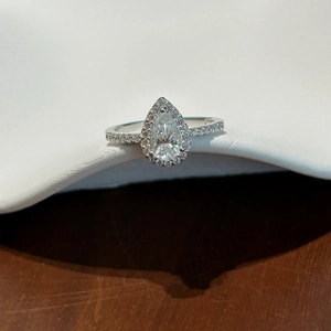 Macro detail of pear-shaped moissanite ring with halo setting and micro-pave diamond band