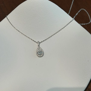 Detail of pear-shaped moissanite pendant necklace with silver halo setting and cable chain
