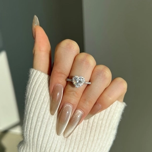 Bague en argent S925 avec moissanite en forme de coeur portée au doigt sur fond en tricot