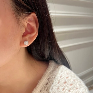 Detailed view of a square-cut moissanite stud earring worn on a female ear lobe