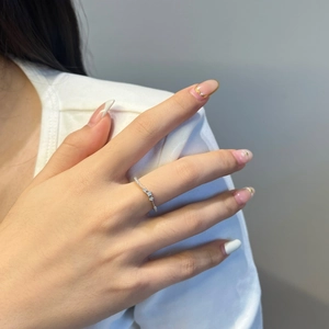Détail d'une bague fine en argent sertie de trois diamants sur le doigt d'un mannequin