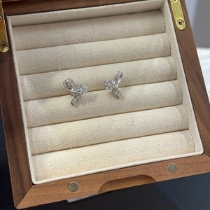 Détail des boucles d'oreilles nœud en argent avec moissanite dans un écrin bois