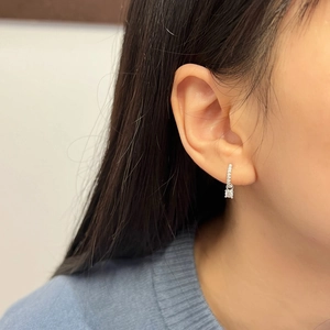 Close-up of S925 sterling silver hoop earrings with round-cut moissanite solitaire pendants
