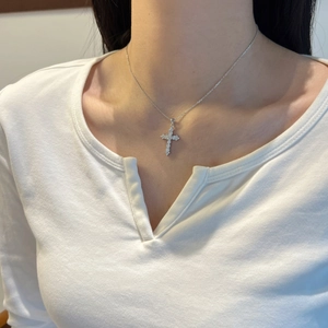 Close-up of a silver cross pendant necklace with sparkling pavé moissanite stones