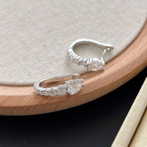 Élégantes boucles d'oreilles cœur en argent 925 et moissanite sur fond bois rustique