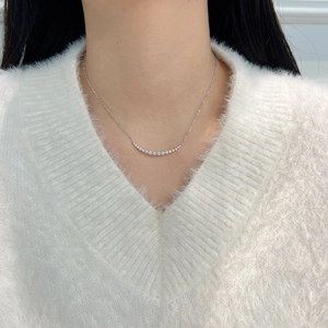 Silver S925 necklace with curved diamond smile pendant worn on a white knit sweater
