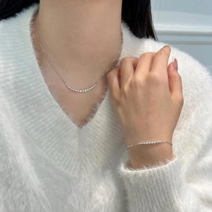Detail view of S925 sterling silver smile necklace and bracelet set on a white sweater