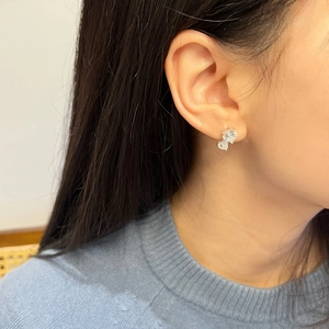 Gros plan de boucles d'oreilles double cœur en argent S925 et moissanite sur l'oreille