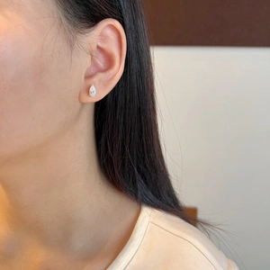 Close-up of a pear-cut moissanite stud earring worn by a model in silver S925 setting