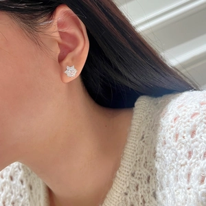 Detail view of S925 silver snowflake earring with moissanite stones on model's ear