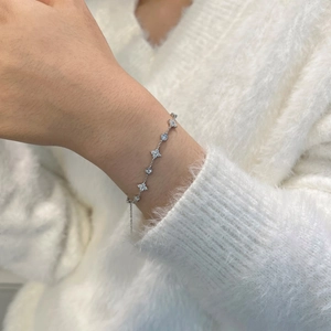 Detail of S925 sterling silver bracelet with floral and round charms on a soft knit sleeve