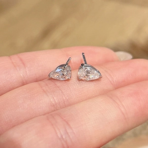Pear cut 2ct moissanite stud earrings in S925 sterling silver held on a fingertip