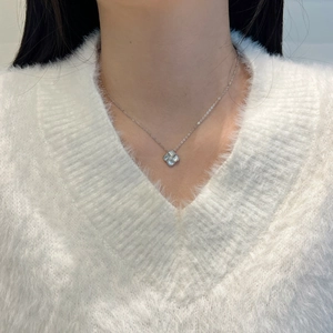 Gros plan du collier trèfle en argent S925 avec nacre blanche sur un pull blanc