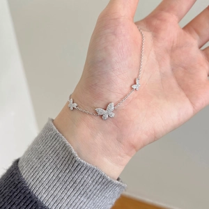 Macro shot of butterfly charm bracelet with cubic zirconia paving on fine silver chain